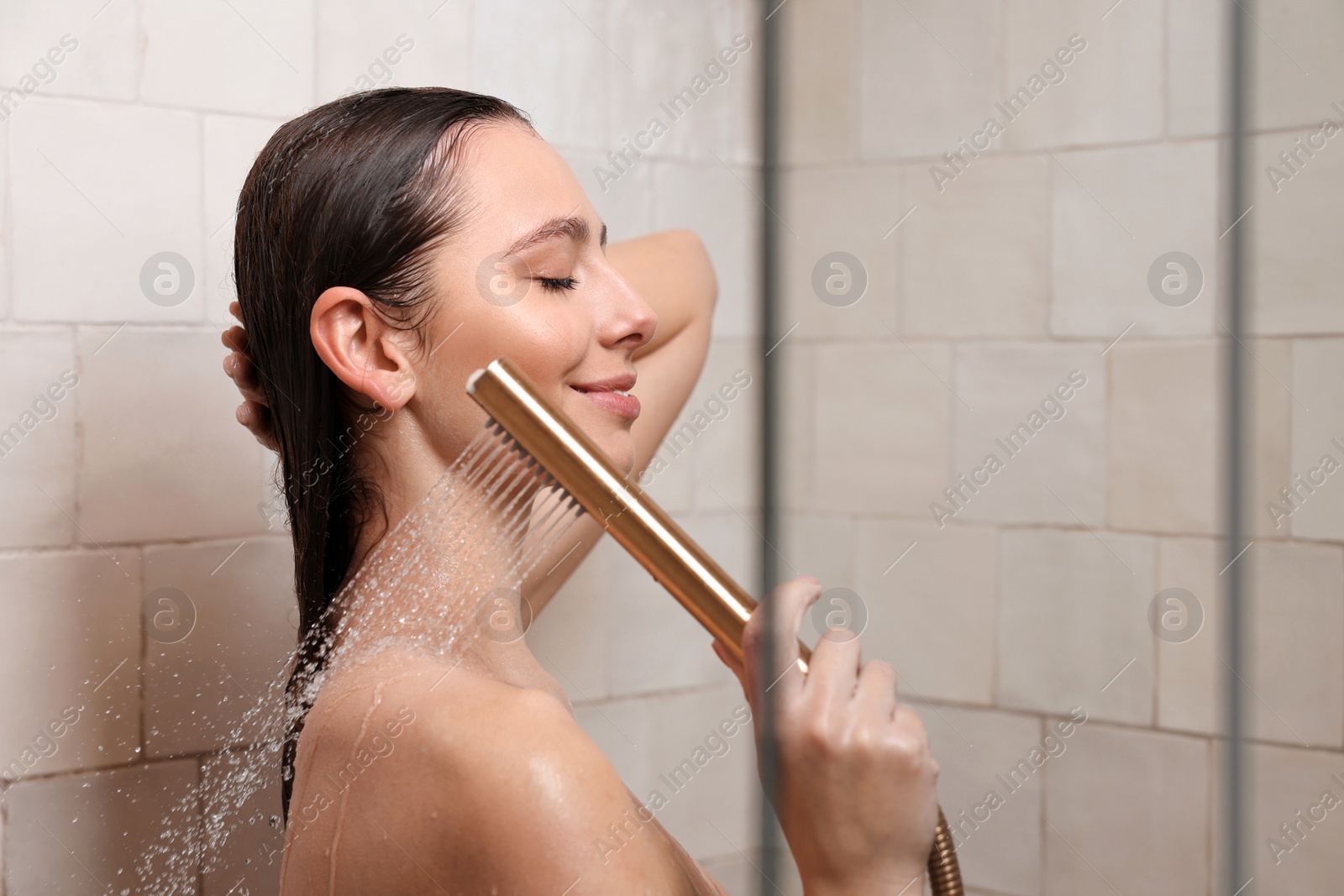 Photo of Happy woman washing hair while taking shower at home