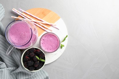 Photo of Delicious blackberry smoothie and berries on white table, top view. Space for text