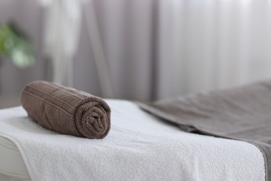 Rolled towel on massage table in spa center, closeup