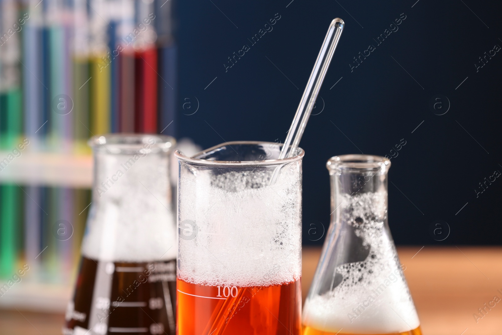 Photo of Laboratory glassware with colorful liquids on blurred background, closeup. Chemical reaction