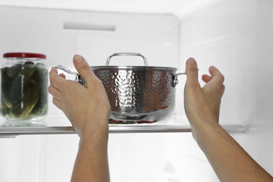 Young woman taking pot out of refrigerator, closeup