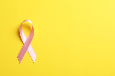 Photo of Pink ribbon on color background, top view. Cancer awareness