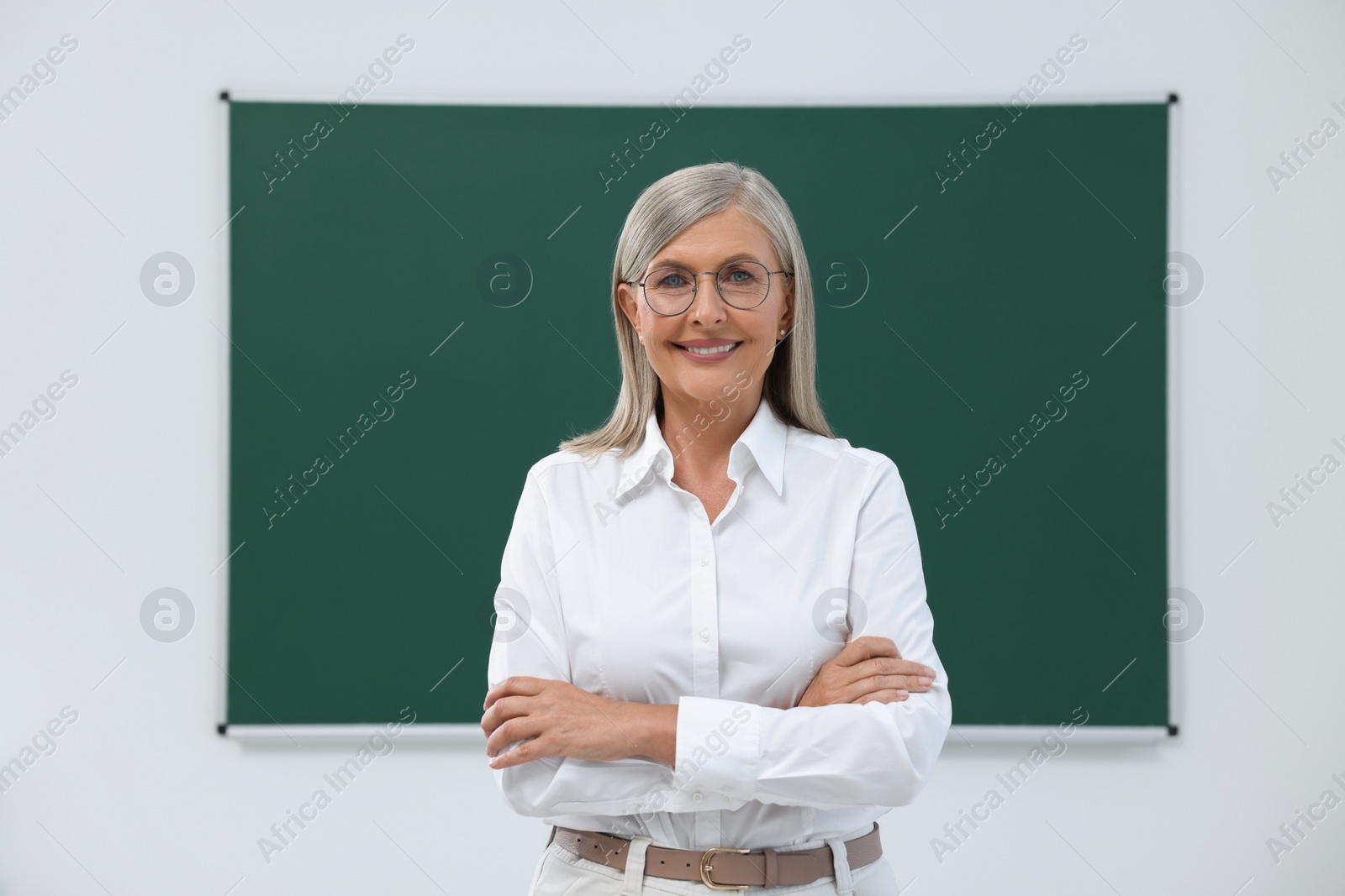 Photo of Portrait of happy professor near blackboard in classroom