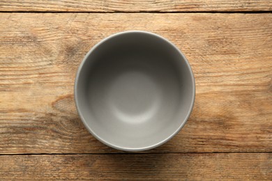 Stylish empty ceramic bowl on wooden table, top view. Cooking utensil