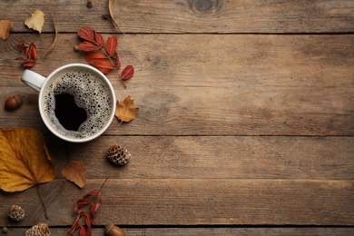 Photo of Cup of hot drink and autumn leaves on wooden table, flat lay with space for text. Cozy atmosphere