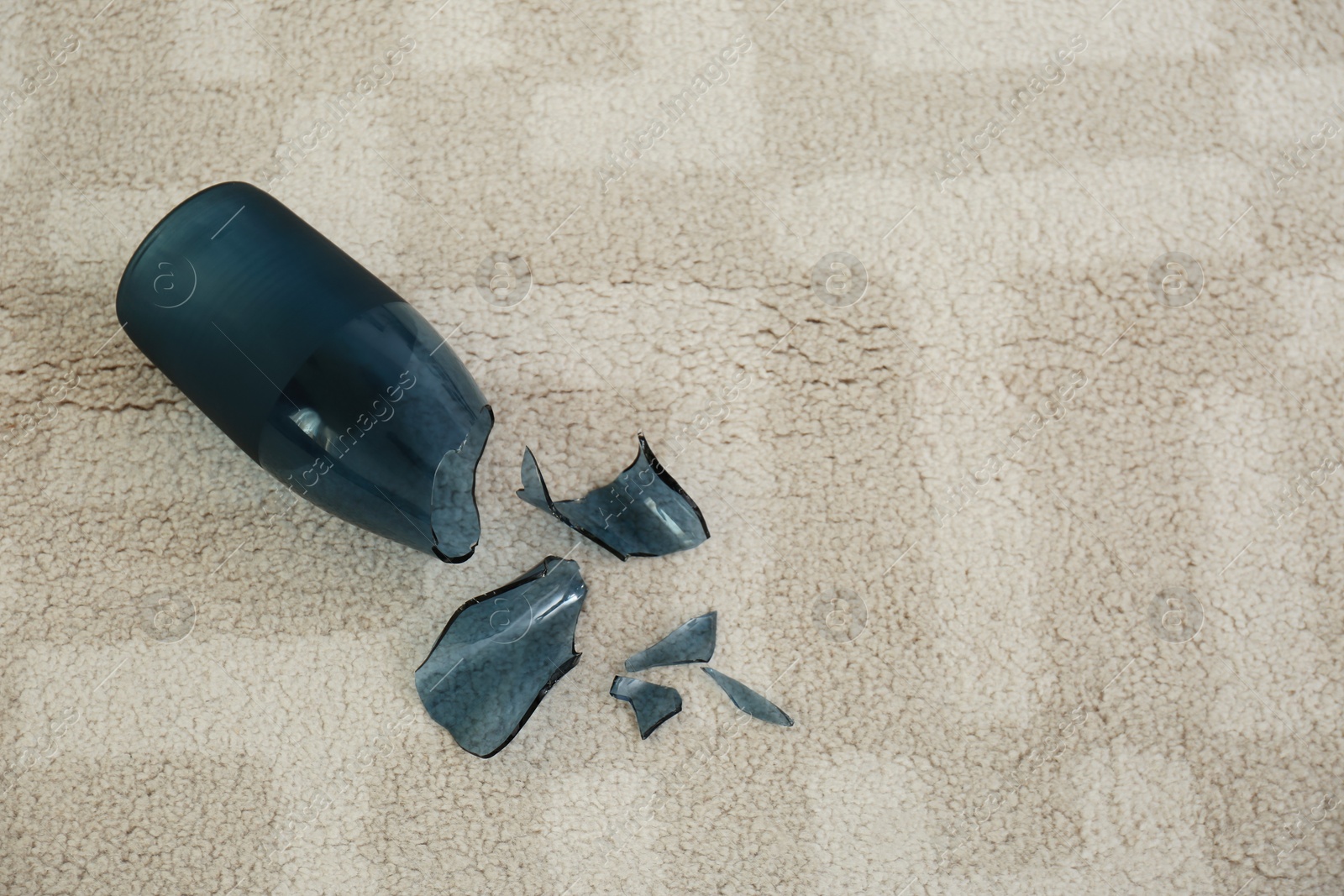 Photo of Broken blue glass vase on carpet, flat lay. Space for text