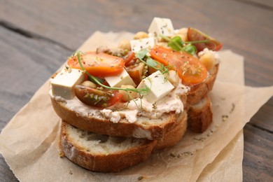 Photo of Tasty vegan sandwich with tomatoes, tofu and chickpeas on wooden table, closeup