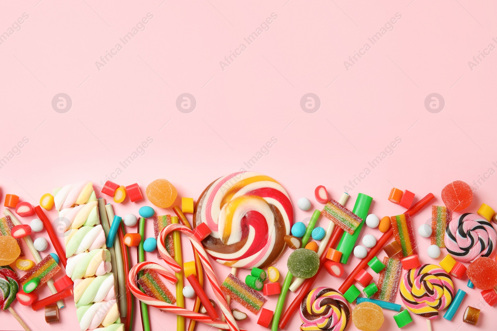 Photo of Flat lay composition with different yummy candies and space for text on color background