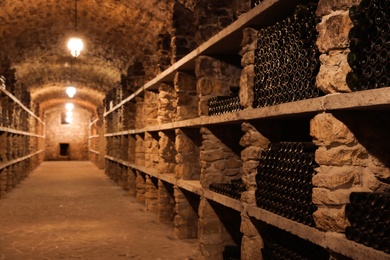 Photo of Wine cellar interior with many bottles on shelves