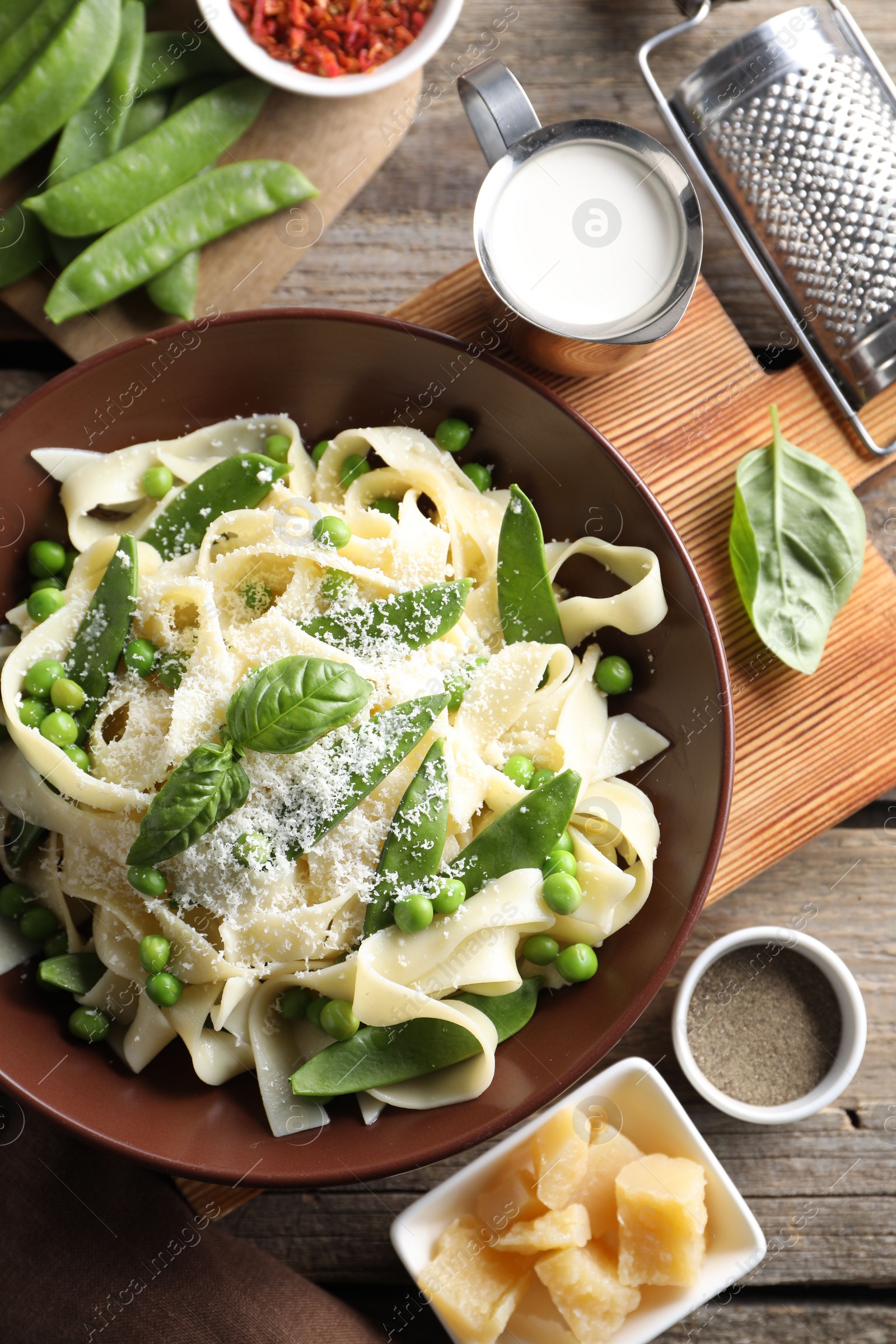 Photo of Delicious pasta with green peas and ingredients on wooden table, flat lay