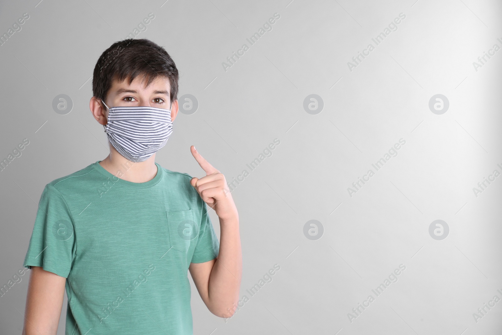 Photo of Boy wearing protective mask on light grey background, space for text. Child safety