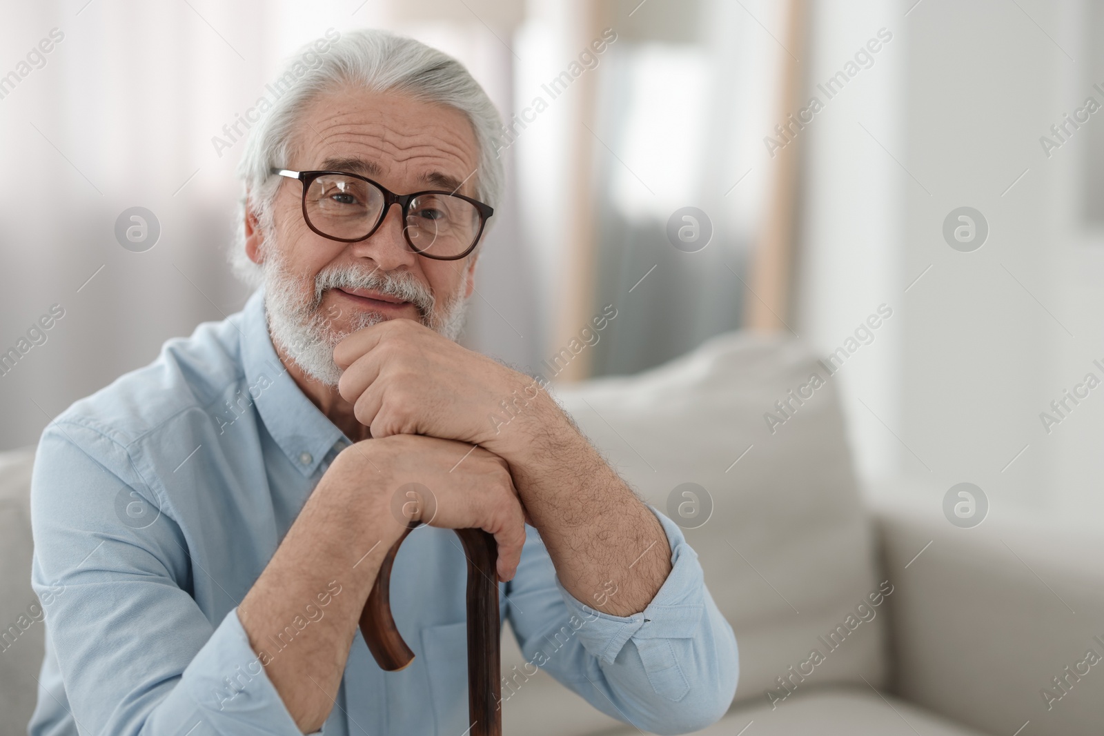 Photo of Portrait of grandpa with glasses and walking cane on sofa indoors