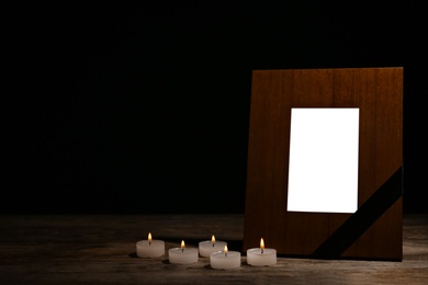 Empty frame with black ribbon and candles on table. Funeral symbol