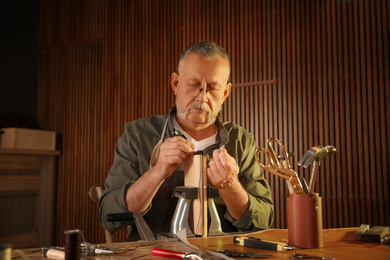 Man sewing piece of leather in workshop