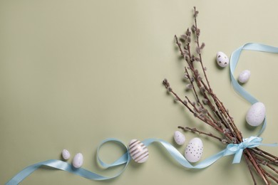 Flat lay composition with festively decorated Easter eggs and pussy willow branches on pale olive color background. Space for text