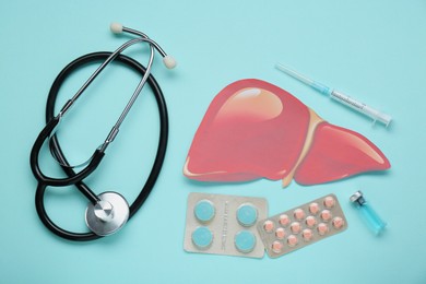 Paper liver and medical supplies on turquoise background, flat lay. Hepatitis treatment