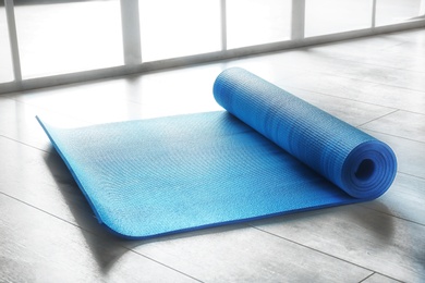 Photo of Rubber yoga mat on floor indoors. Space for text