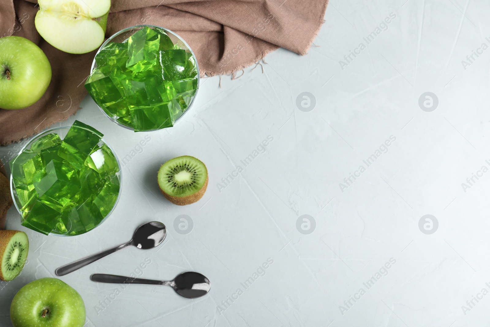 Photo of Flat lay composition with green fruit jelly in bowls on light table. Space for text