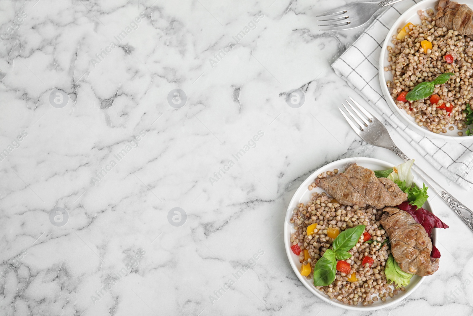 Photo of Tasty buckwheat porridge with meat on white marble table, flat lay. Space for text