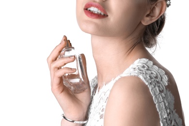 Beautiful young bride with bottle of perfume on white background, closeup