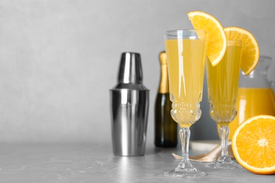 Photo of Glasses of Mimosa cocktail with garnish on marble table. Space for text