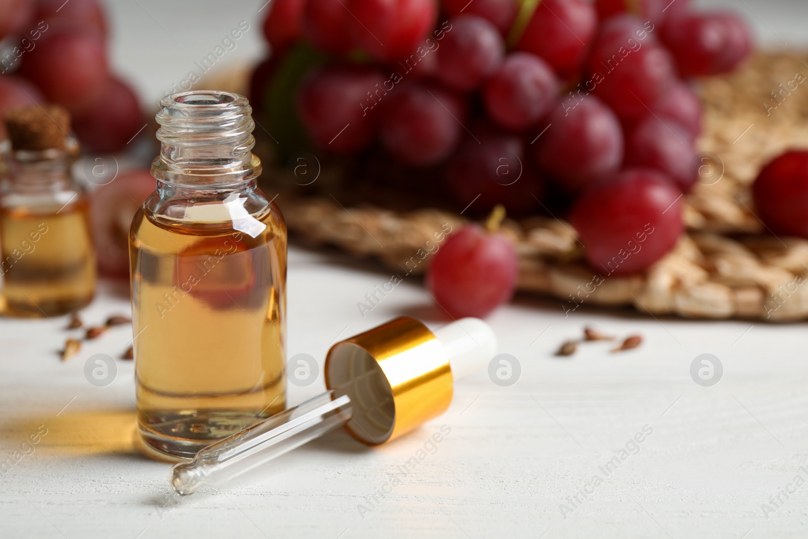 Photo of Bottle of natural grape seed oil on white wooden table. Organic cosmetic