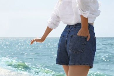 Photo of Young woman near sea on summer day, closeup. Space for text
