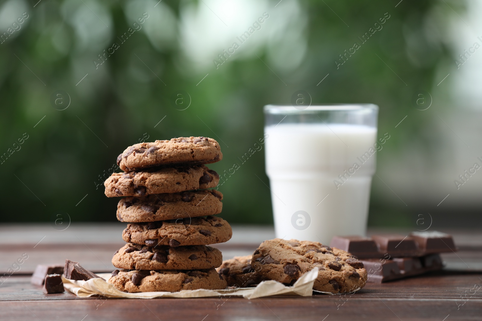 Photo of Delicious chocolate chip cookies and glass of milk on wooden table