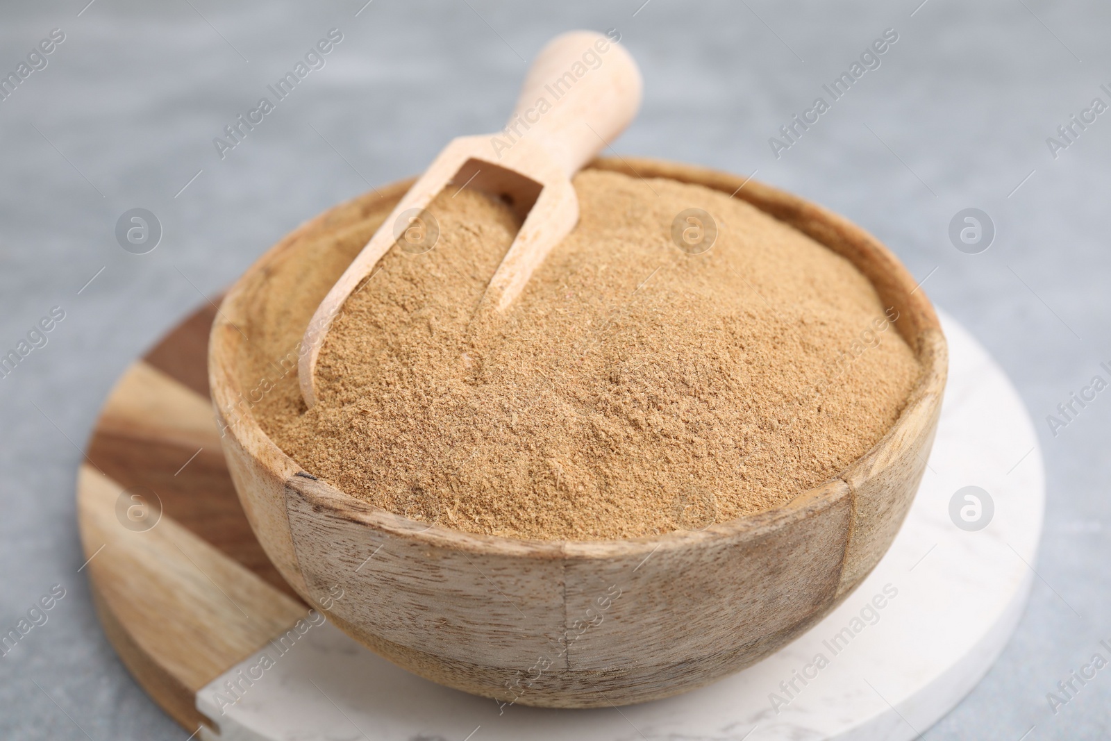 Photo of Dietary fiber. Psyllium husk powder in bowl and scoop on grey table, closeup