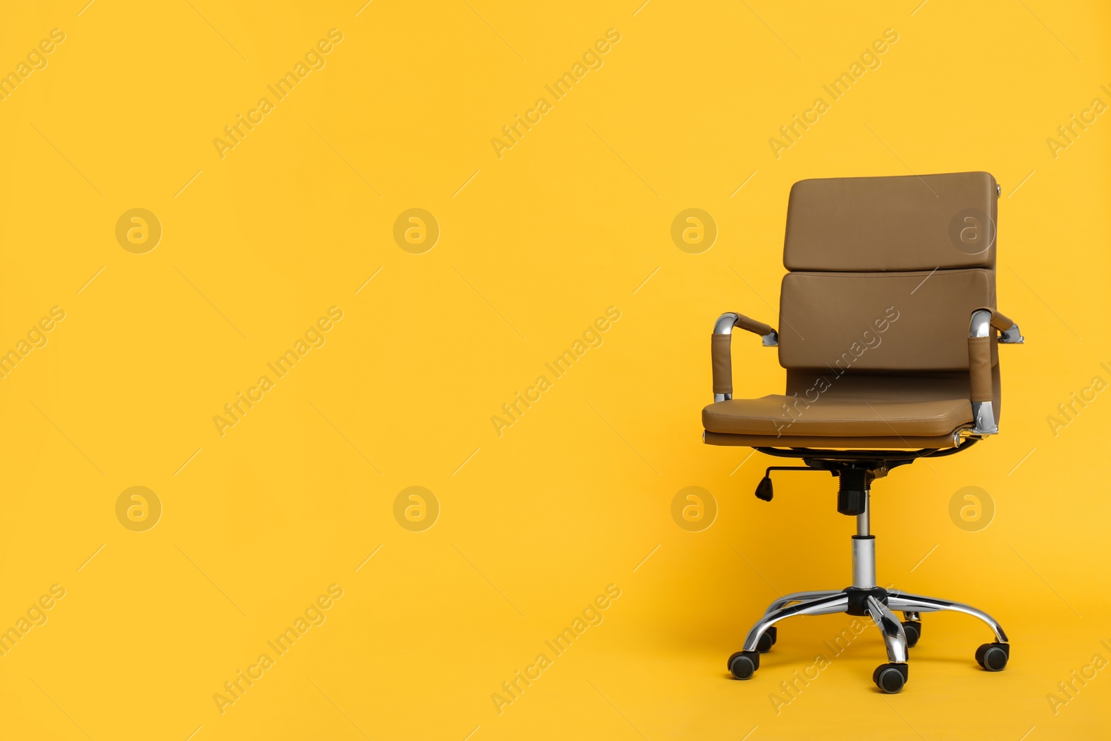 Photo of Modern office chair on yellow background. Space for text