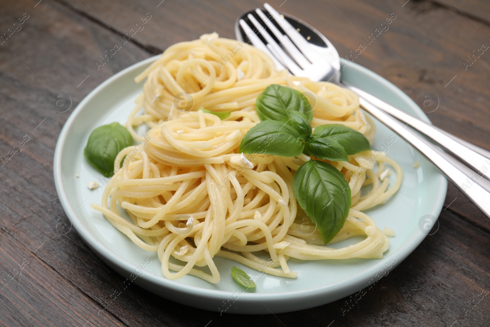 Photo of Delicious pasta with brie cheese and basil leaves on wooden table, closeup