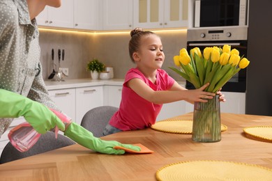 Spring cleaning. Mother and daughter tidying up in kitchen