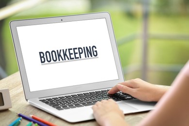 Image of Bookkeeping concept. Woman working with laptop at wooden table, closeup