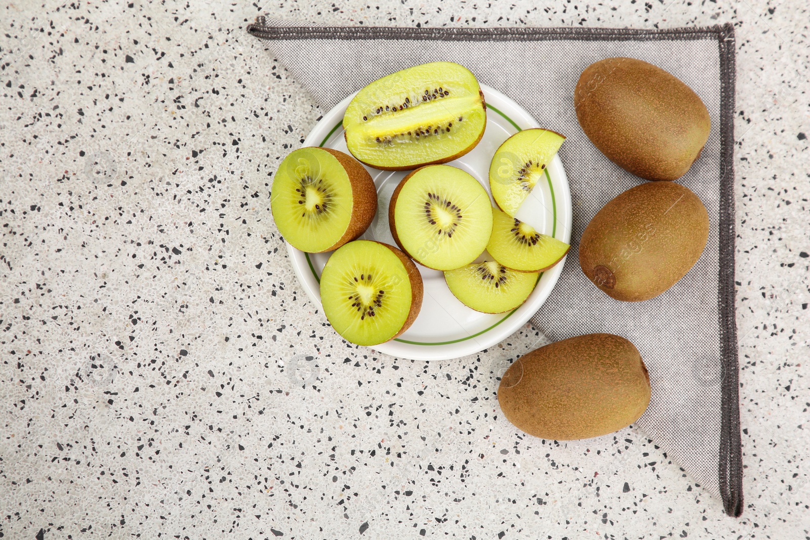 Photo of Whole and cut fresh kiwis on white table with pattern, flat lay. Space for text