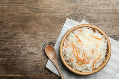 Tasty fermented cabbage on wooden table, flat lay. Space for text