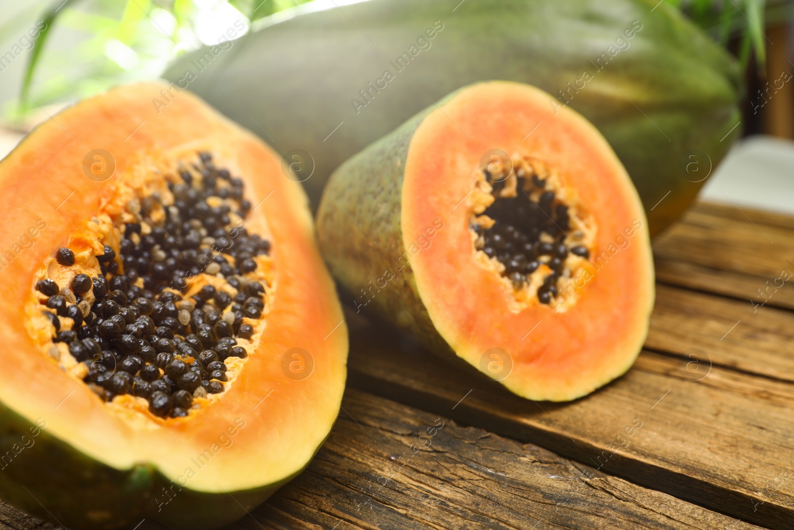 Photo of Fresh juicy papayas on wooden table against blurred background, closeup view