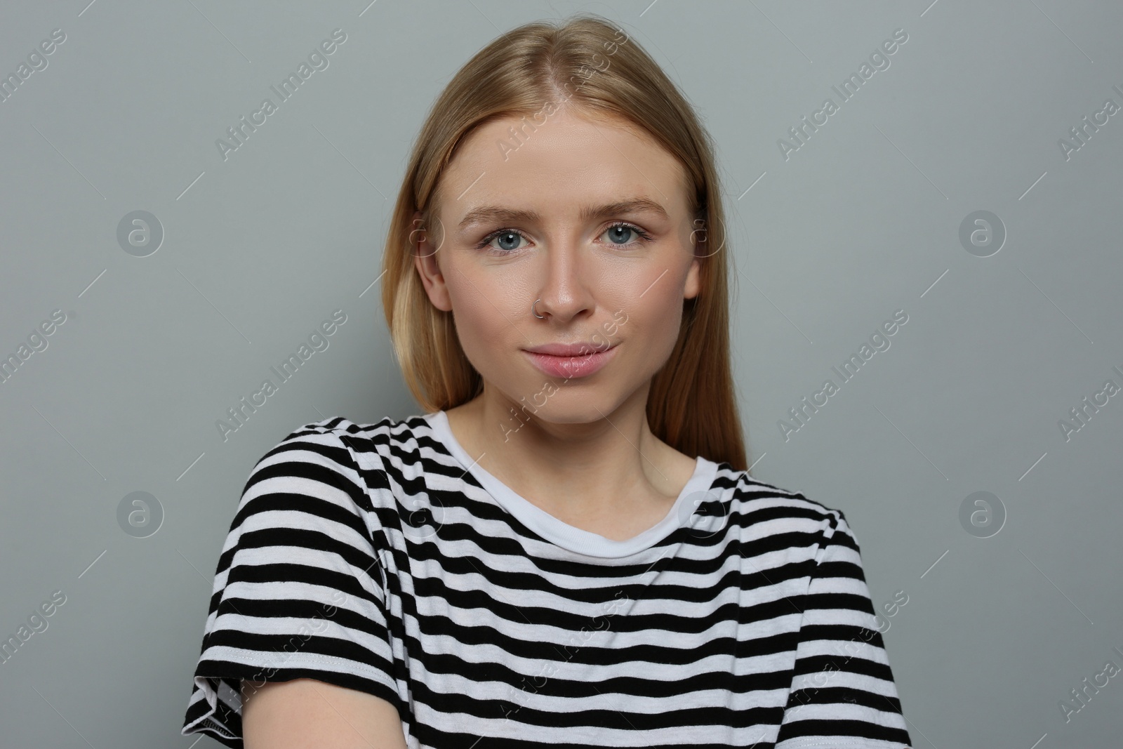 Photo of Portrait of beautiful young woman in striped t-shirt on grey background