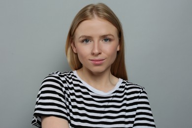 Portrait of beautiful young woman in striped t-shirt on grey background
