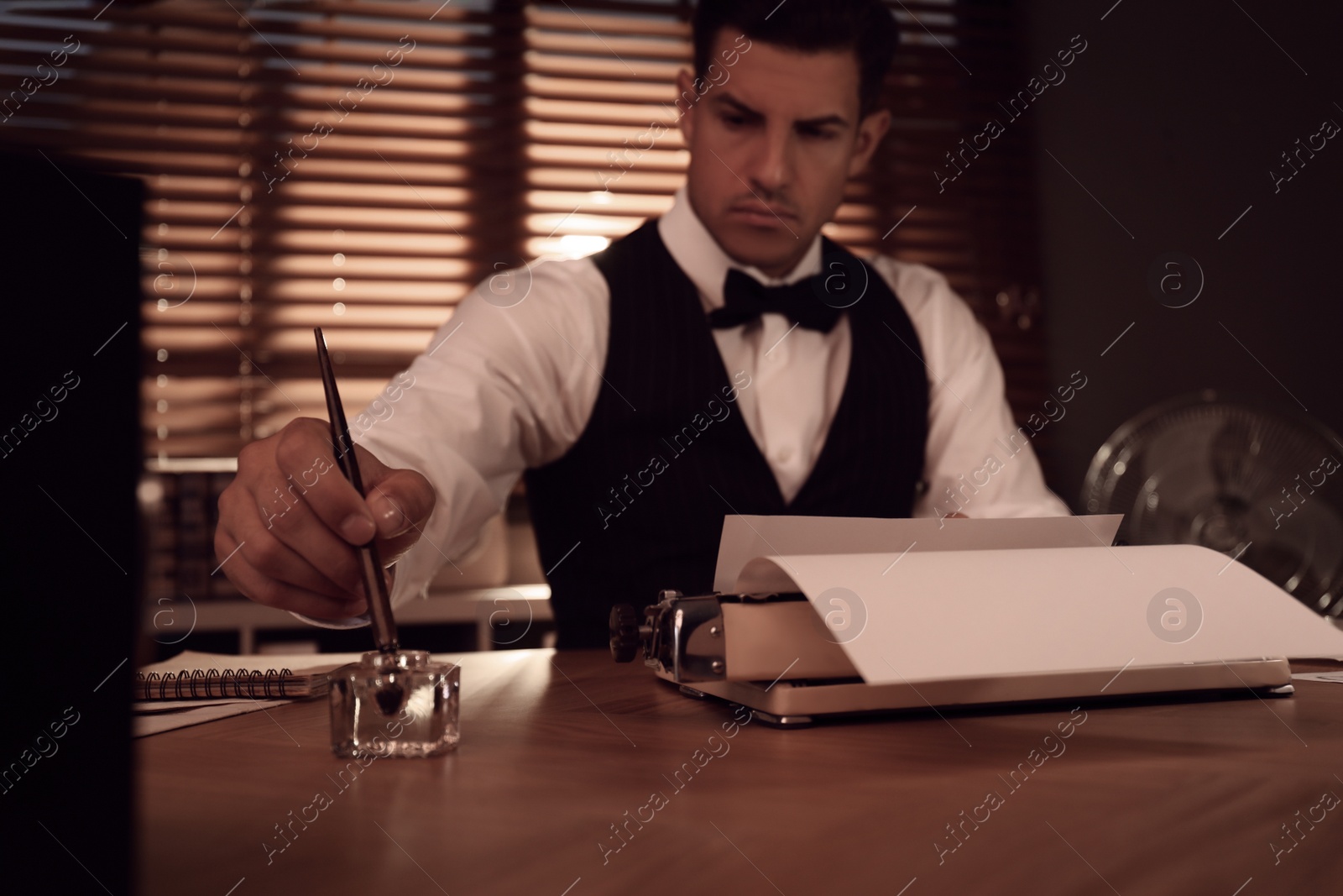 Photo of Old fashioned detective working at table in office, focus on hand with ink pen