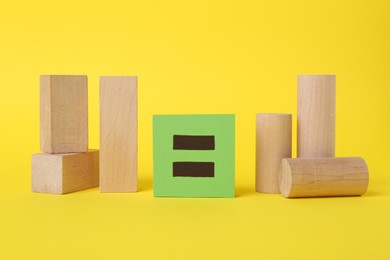 Photo of Wooden blocks and equals sign on yellow background