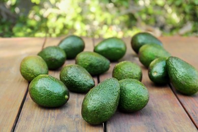 Photo of Tasty ripe avocados on wooden table outdoors