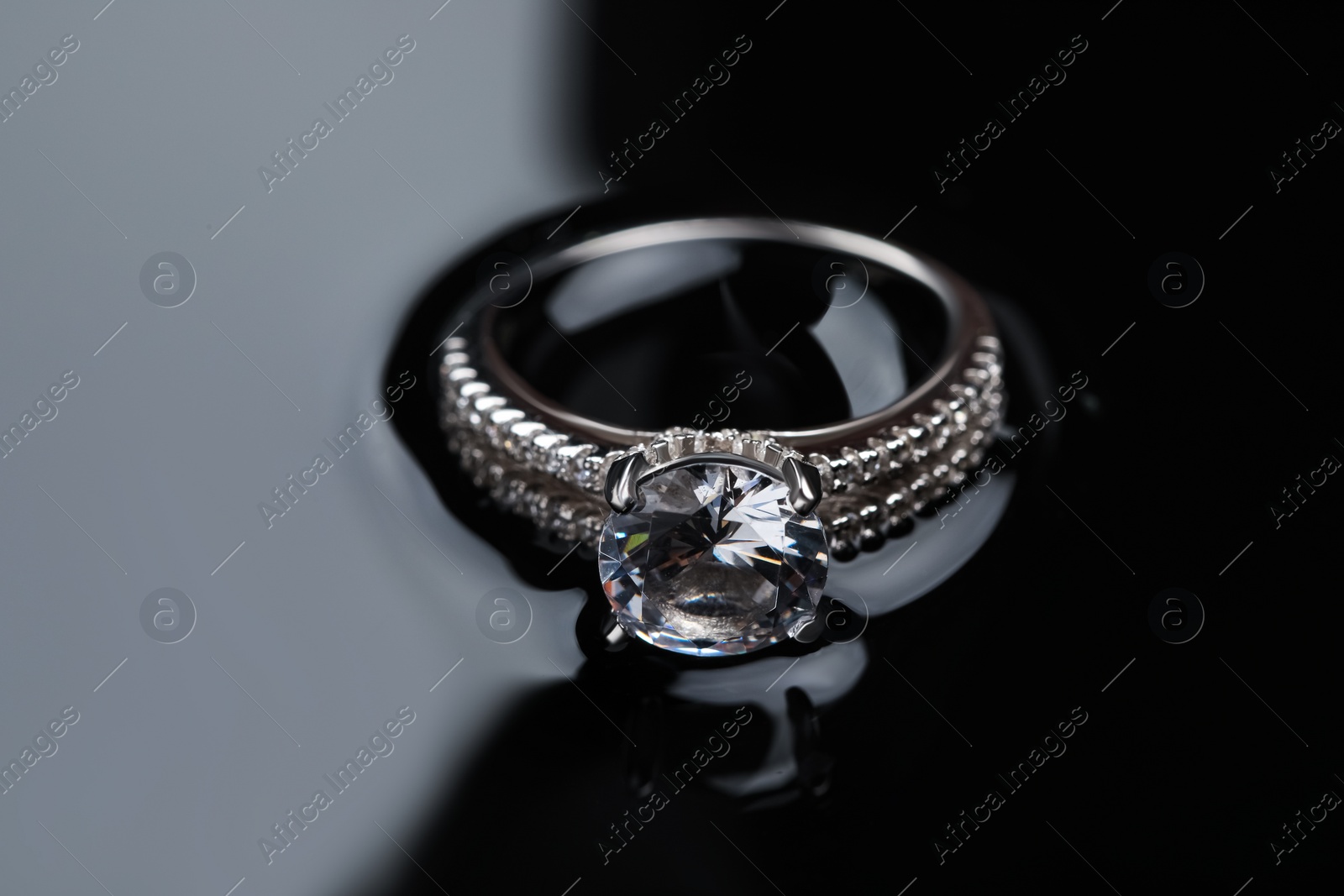 Photo of Luxury jewelry. Elegant ring on black mirror surface, closeup