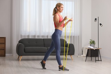 Photo of Fit woman doing exercise with fitness elastic band at home