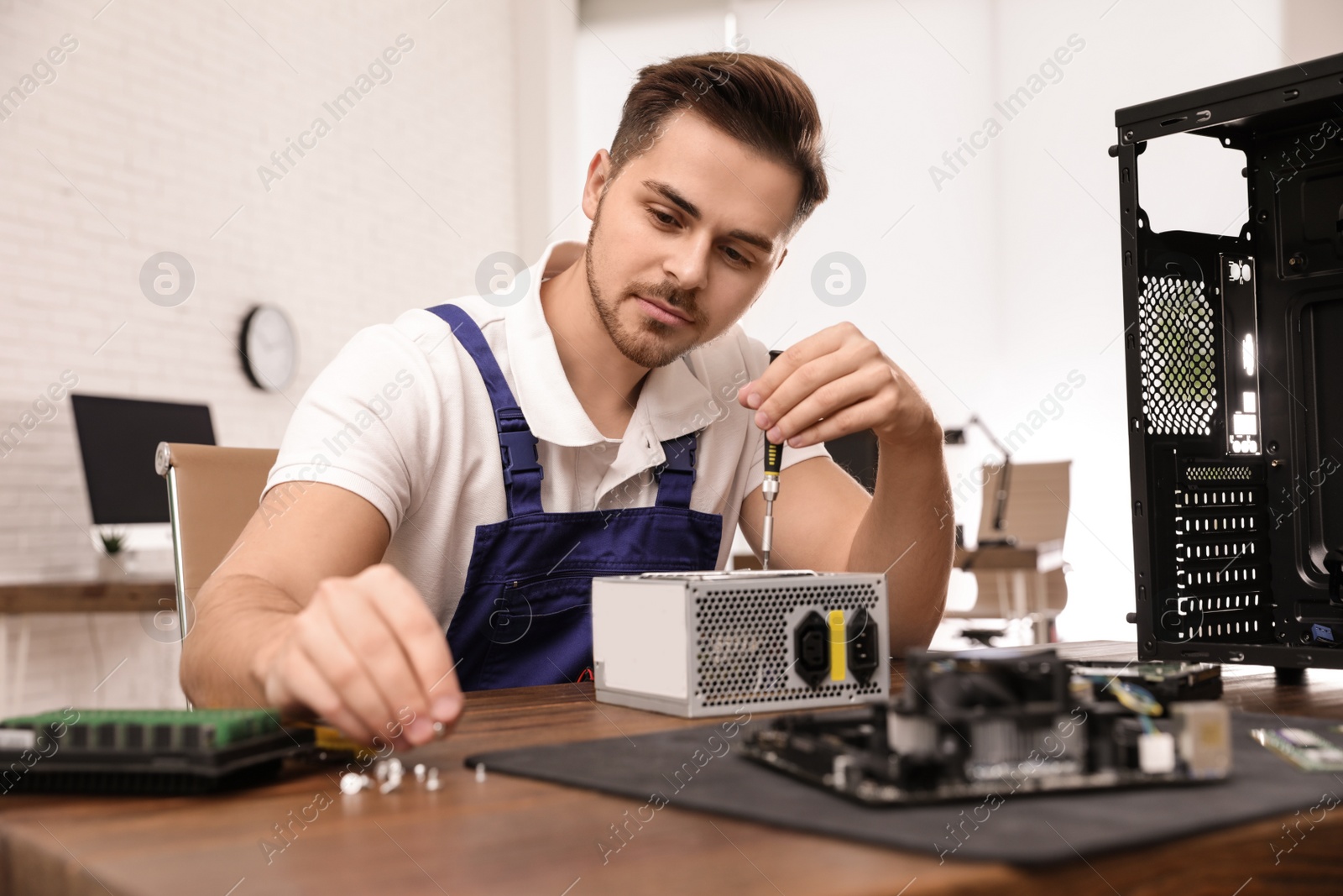 Photo of Male technician repairing power supply unit at table indoors