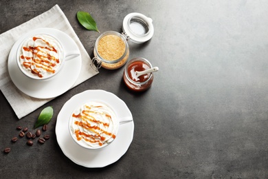 Cups of coffee with caramel topping on grey background, top view