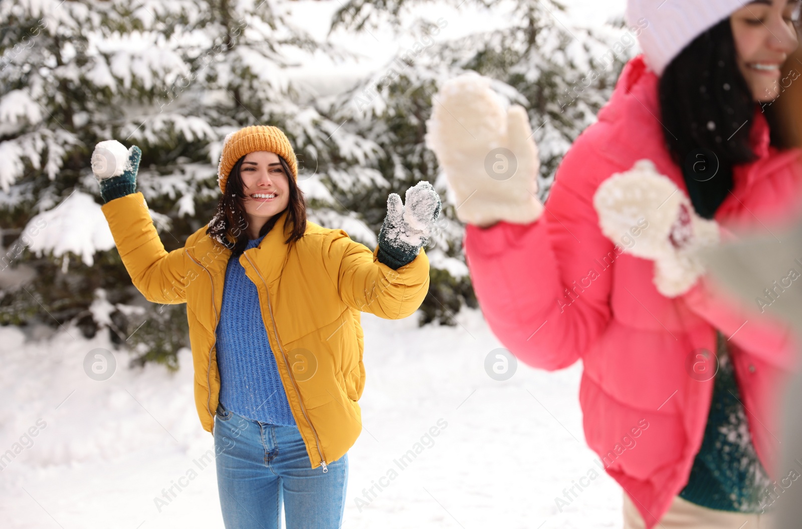 Photo of Happy friends playing snowballs outdoors. Winter vacation