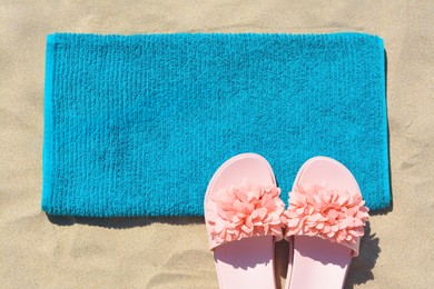 Photo of Towel and flip flops on sand, flat lay. Beach accessories