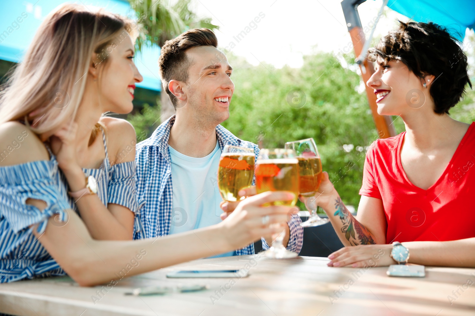 Photo of Young people with glasses of cold beer at table