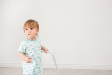 Photo of Cute baby playing with toy walker indoors