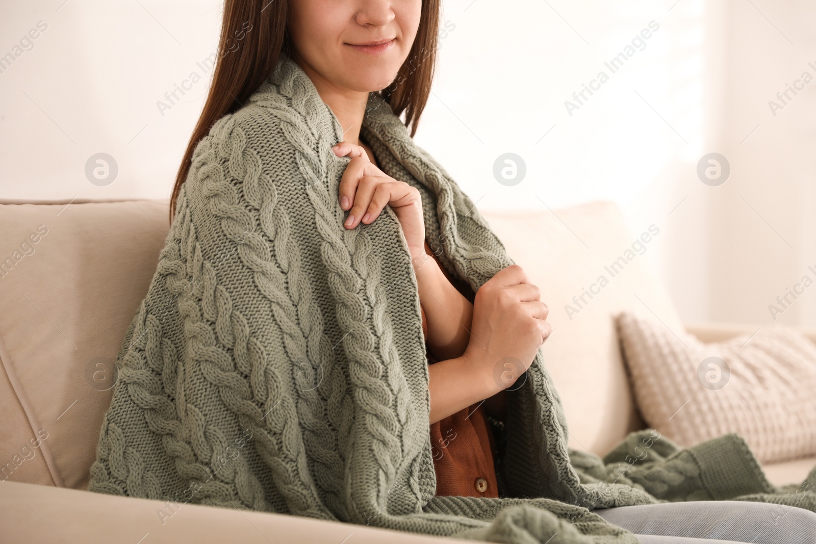 Photo of Woman covered with warm green plaid sitting on sofa indoors, closeup